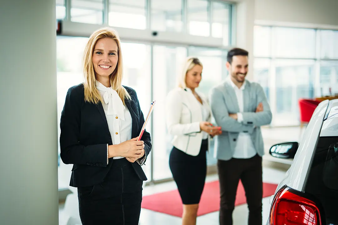 Smiling sales lady selling new car to happy couple